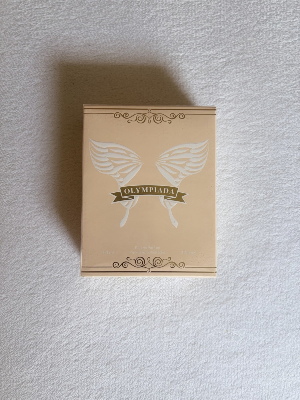 Olympiada cream with white butterfly graphic and banner reading ‘OLYMPIADA’